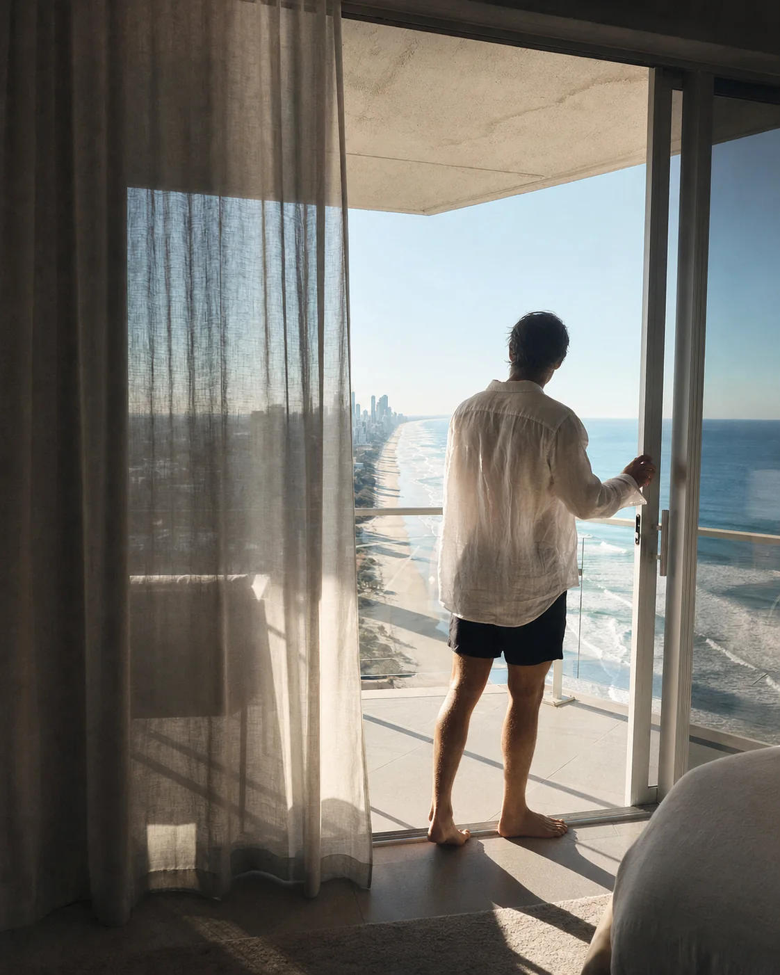 A guest opening the balcony to the Surfers Paradise coast